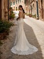 Bride looking over shoulder in a mermaid wedding dress with illusion bateau back and sweep train