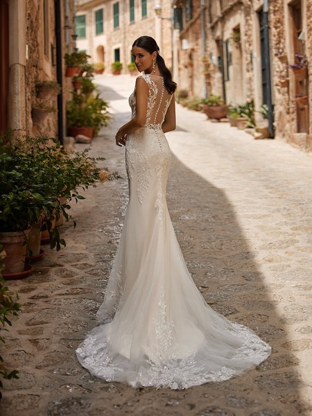 Bride looking over shoulder in a mermaid wedding dress with illusion bateau back and sweep train