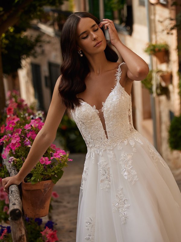 Closeup of bride's wedding dress with side bodice cutouts, sweetheart neckline, and thin spaghetti straps