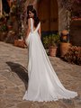 Back view of bride in ivory crepe wedding dress with chiffon pleated detail along v-neckline and chapel chiffon train